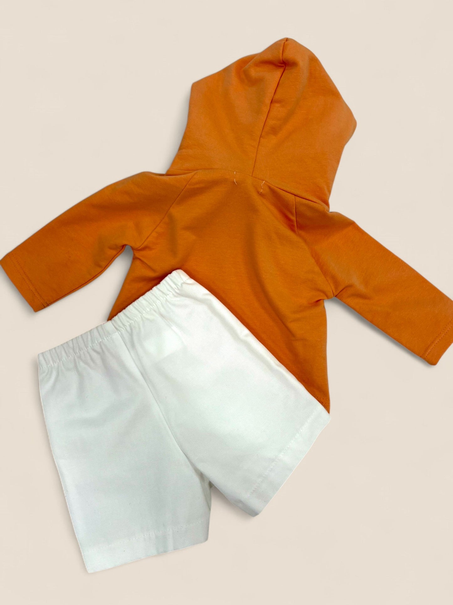 Conjunto sudadera naranja y short blanco.