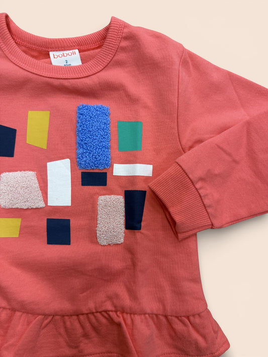 Sudadera rosa con formas geométricas y volante