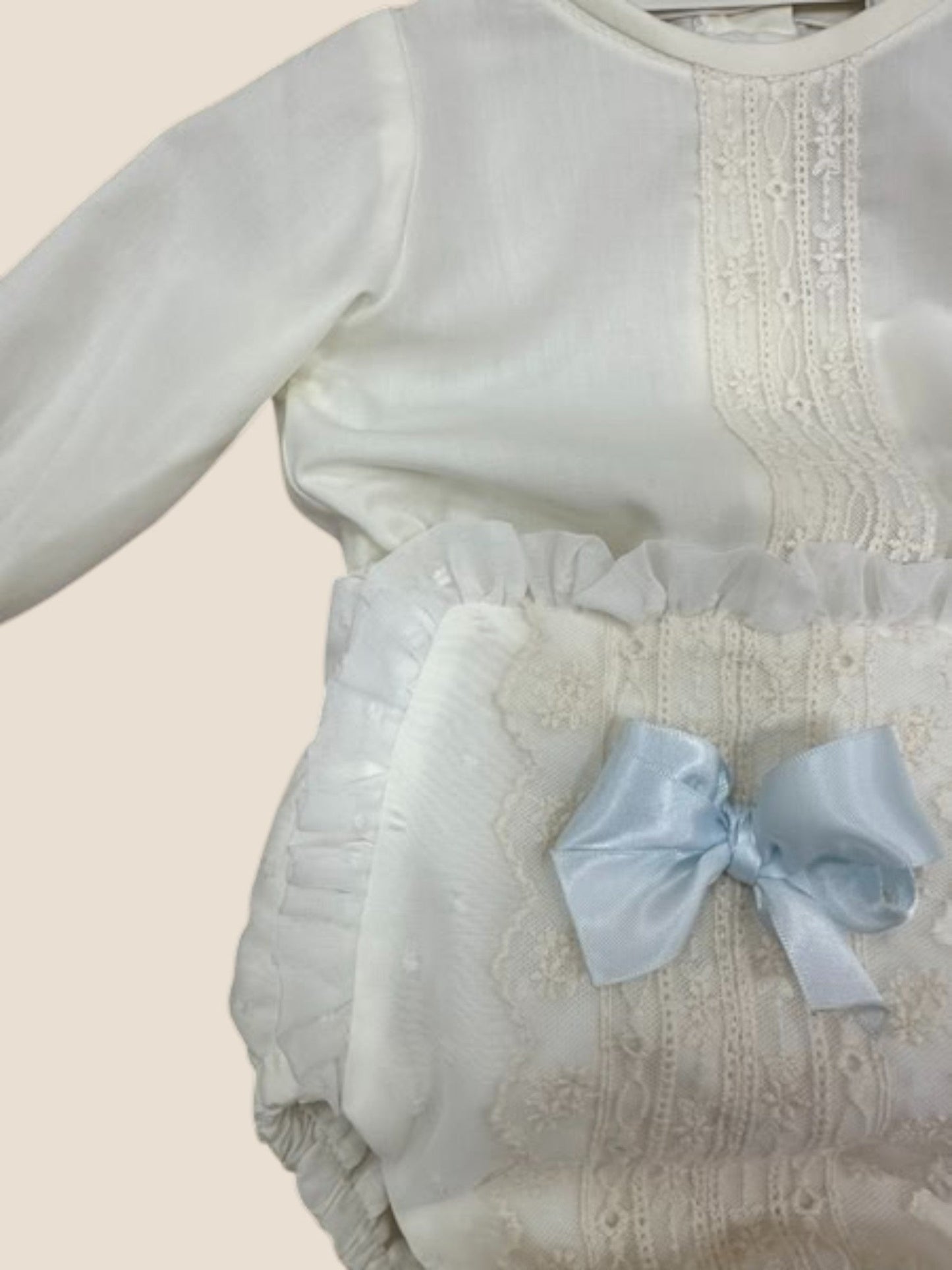 Conjunto bebé en blanco roto con puntilla bordada y lazo azul celeste Eva Martinez