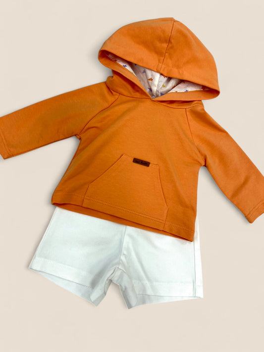 Conjunto sudadera naranja y short blanco.